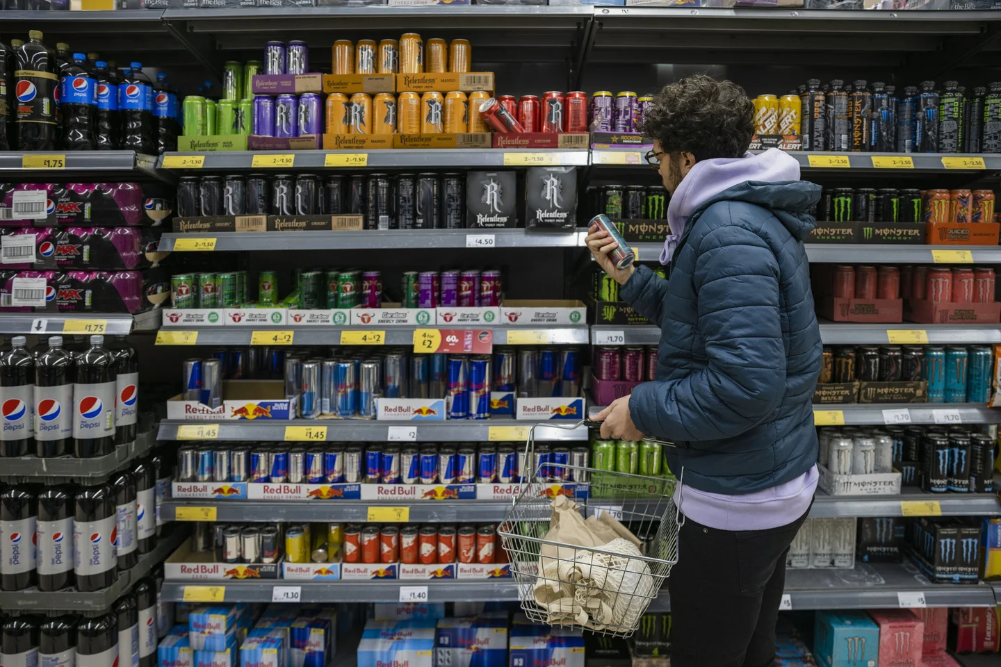 Un adolescent devant un étalage de boissons énergisantes.